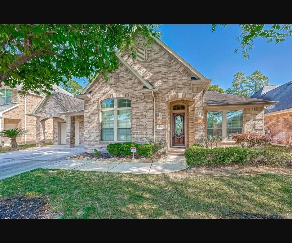 Front exterior with a masonry porch and porte-cochere at a one and a half story home in Eagle Springs, Humble, Texas
