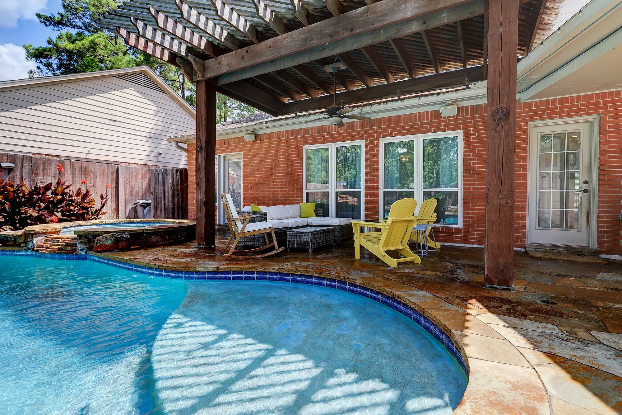 Pool, spa and covered pergola patio behind a brick pool home in Elm Grove Village, Kingwood, Texas