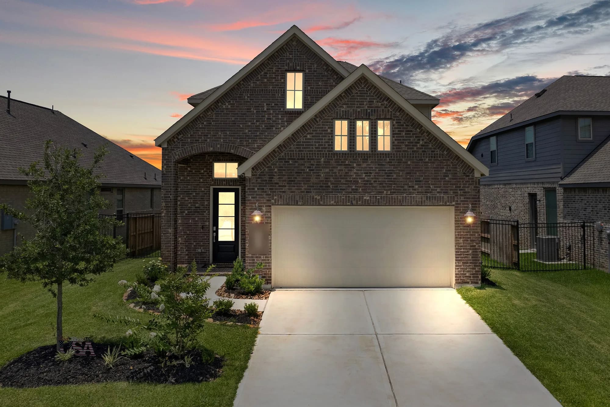 Front exterior at twilight of a two story brick new construction home in Royal Brook, Porter, Texas